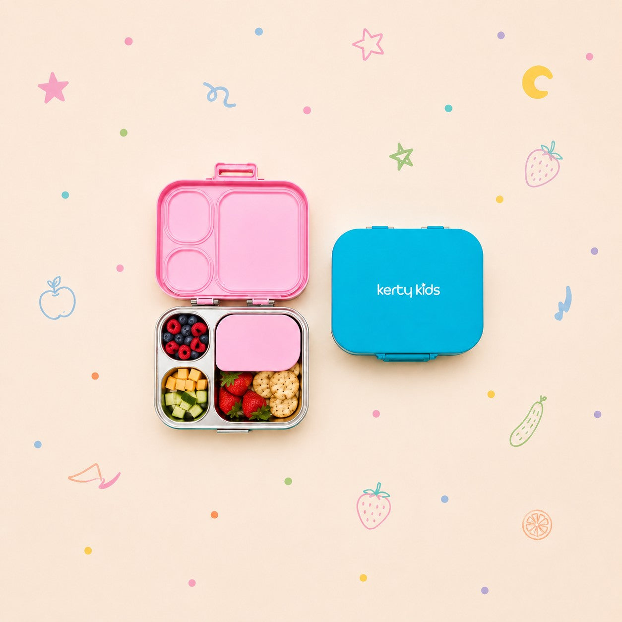 A Kerty Kids lunch box set shown on a pastel background with scattered fruit and candy illustrations. The set includes an open pink compartment lunch box with mixed snacks inside, and a closed bright blue lunch box with the Kerty Kids logo printed in white.