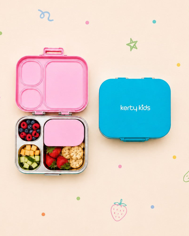 A Kerty Kids lunch box set shown on a pastel background with scattered fruit and candy illustrations. The set includes an open pink compartment lunch box with mixed snacks inside, and a closed bright blue lunch box with the Kerty Kids logo printed in white.